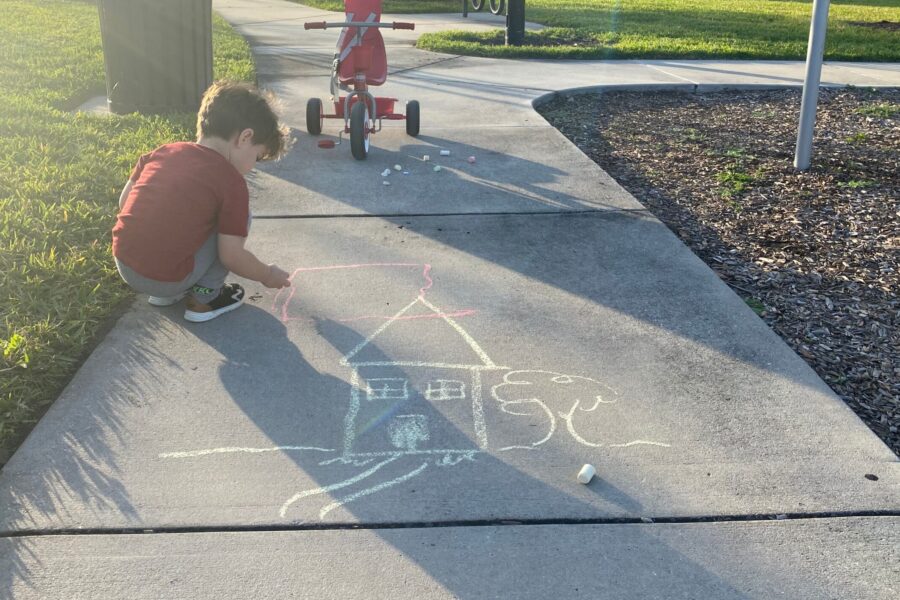 Boy drawing house with chalk at the park